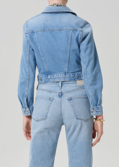 Person wearing a denim jacket and jeans on a plain background