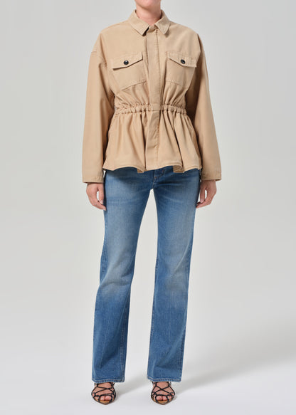 Person wearing a beige jacket and blue jeans on a white background