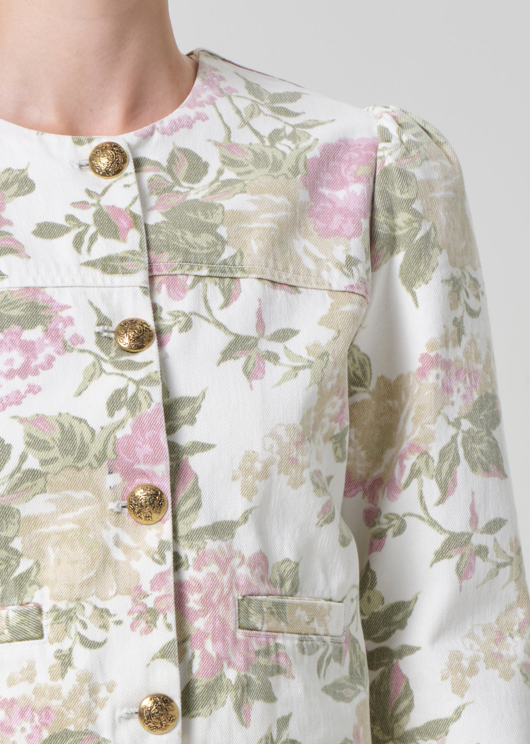 Person wearing a floral jacket and white shorts on a gray background