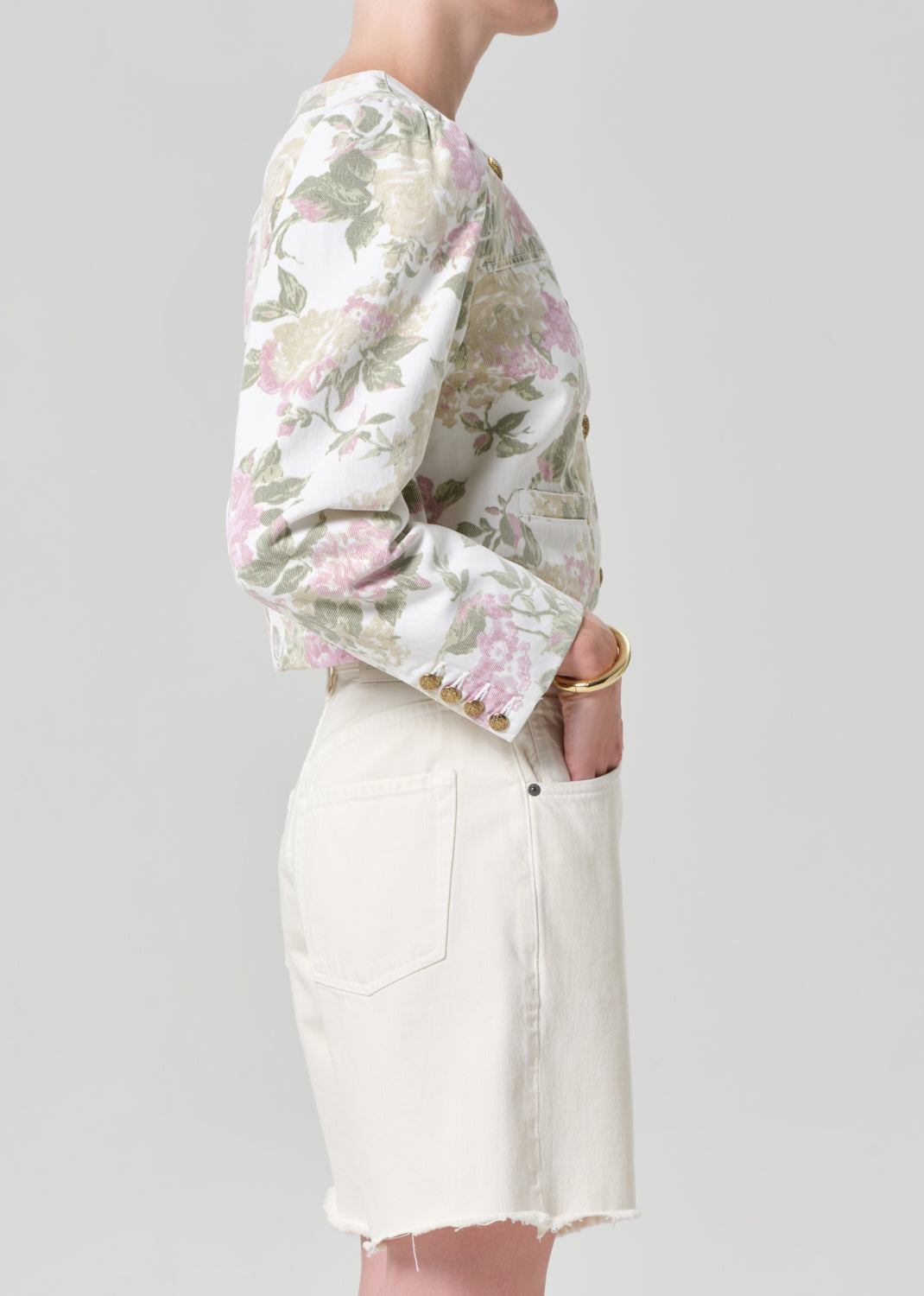 Person wearing a floral jacket and white shorts on a gray background