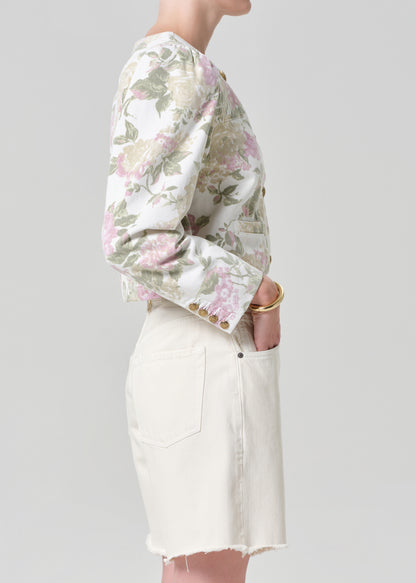 Person wearing a floral jacket and white shorts on a gray background
