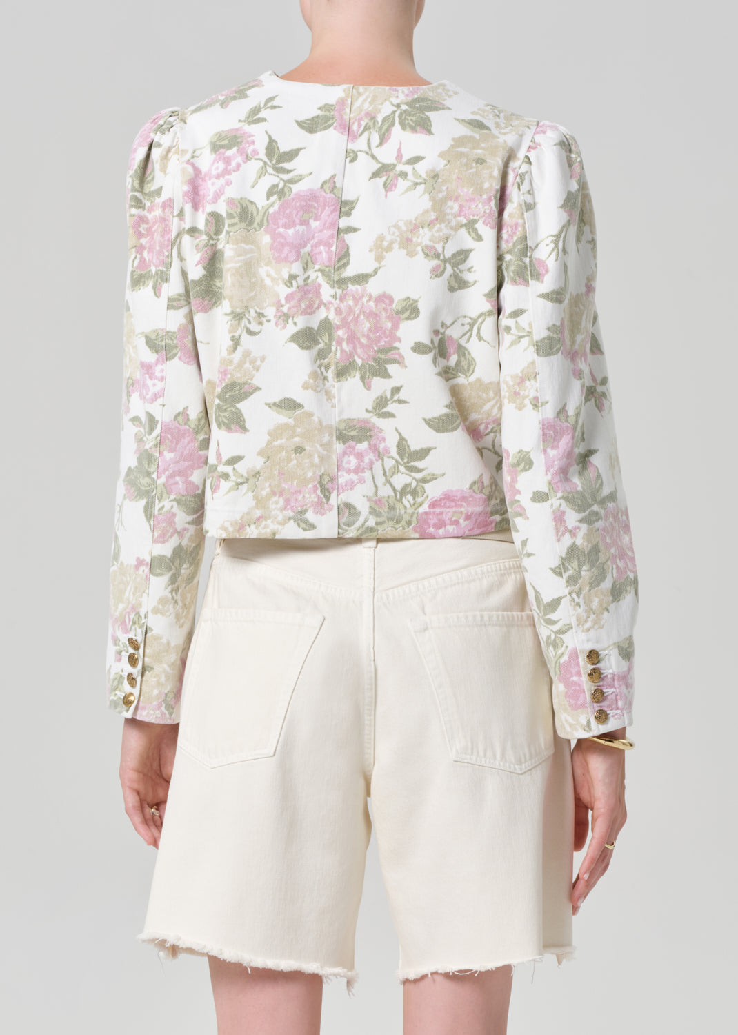 Person wearing a floral jacket and white shorts on a gray background