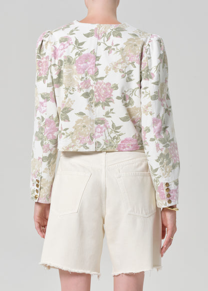 Person wearing a floral jacket and white shorts on a gray background