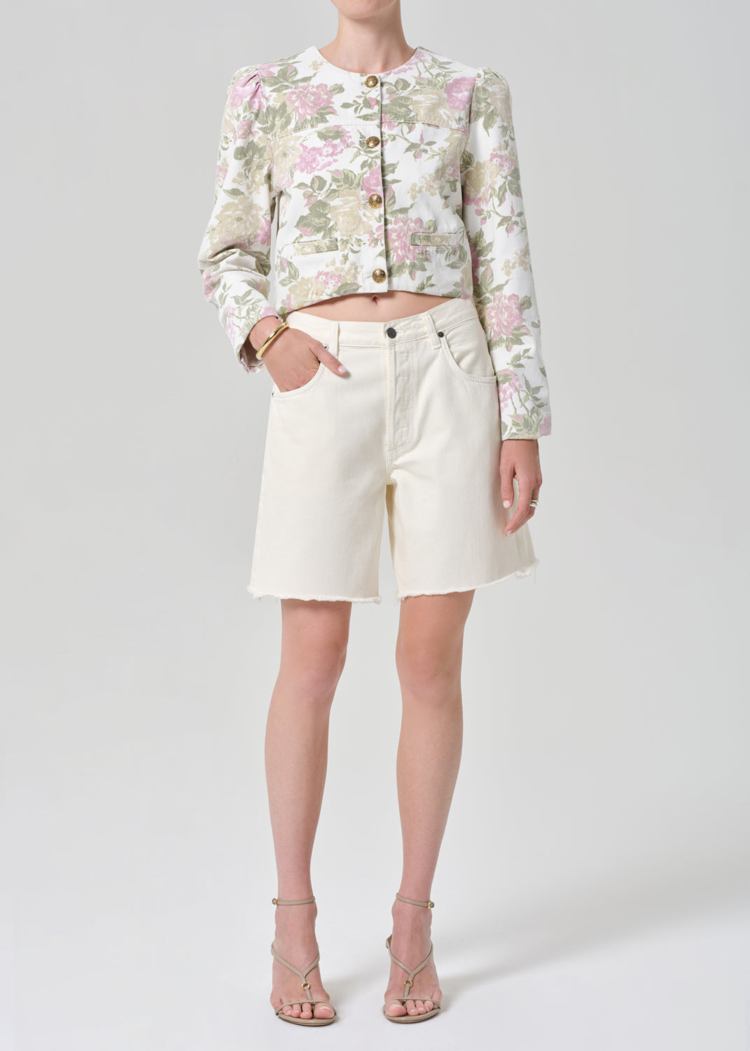 Person wearing a floral jacket and white shorts on a gray background