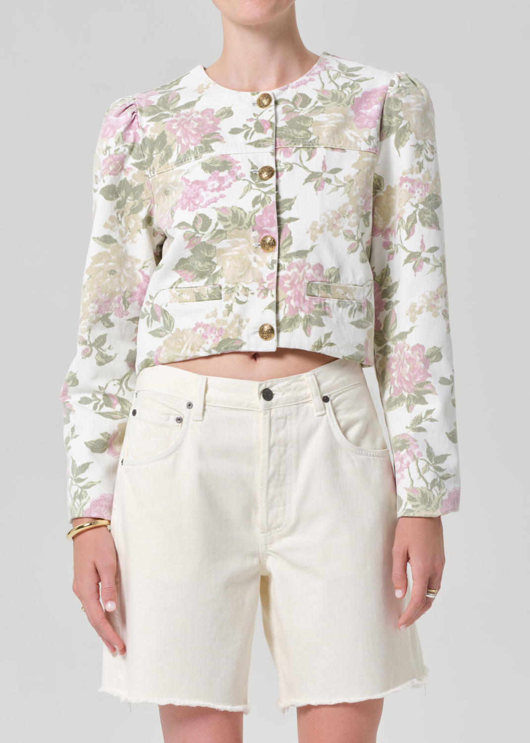 Person wearing a floral jacket and white shorts on a gray background