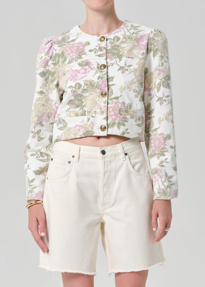 Person wearing a floral jacket and white shorts on a gray background