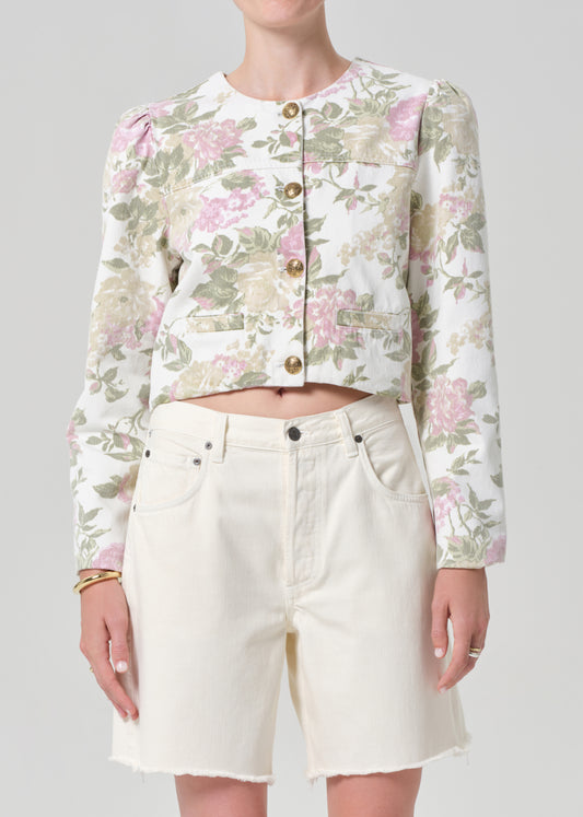 Person wearing a floral jacket and white shorts on a gray background