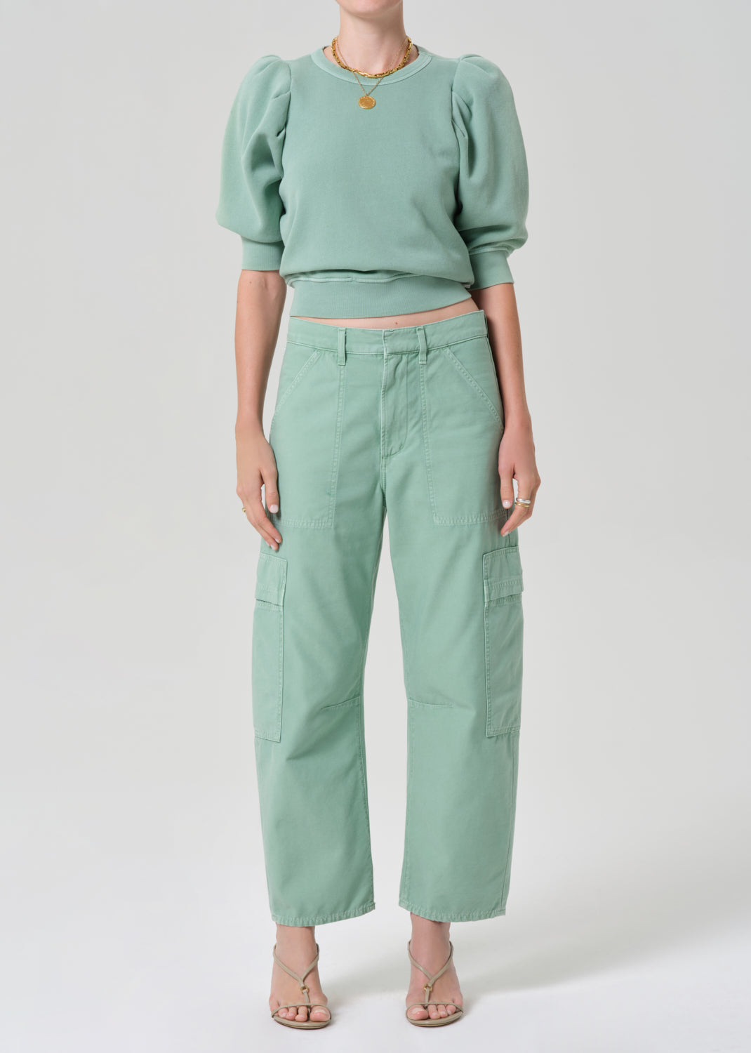 Person wearing a matching green sweater and cargo pants on a light gray background