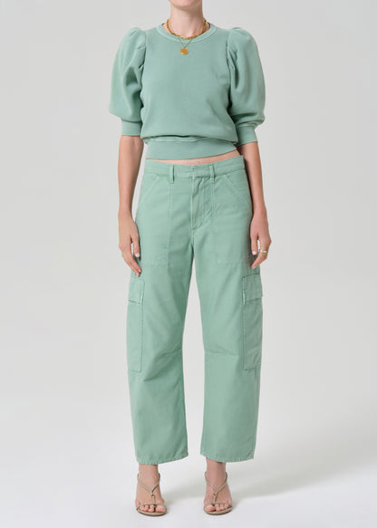 Person wearing a matching green sweater and cargo pants on a light gray background