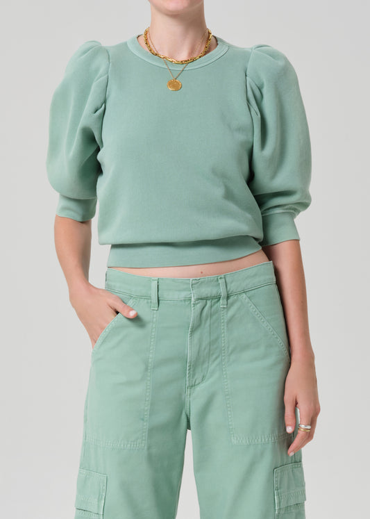 Person wearing a matching green sweater and cargo pants on a light gray background