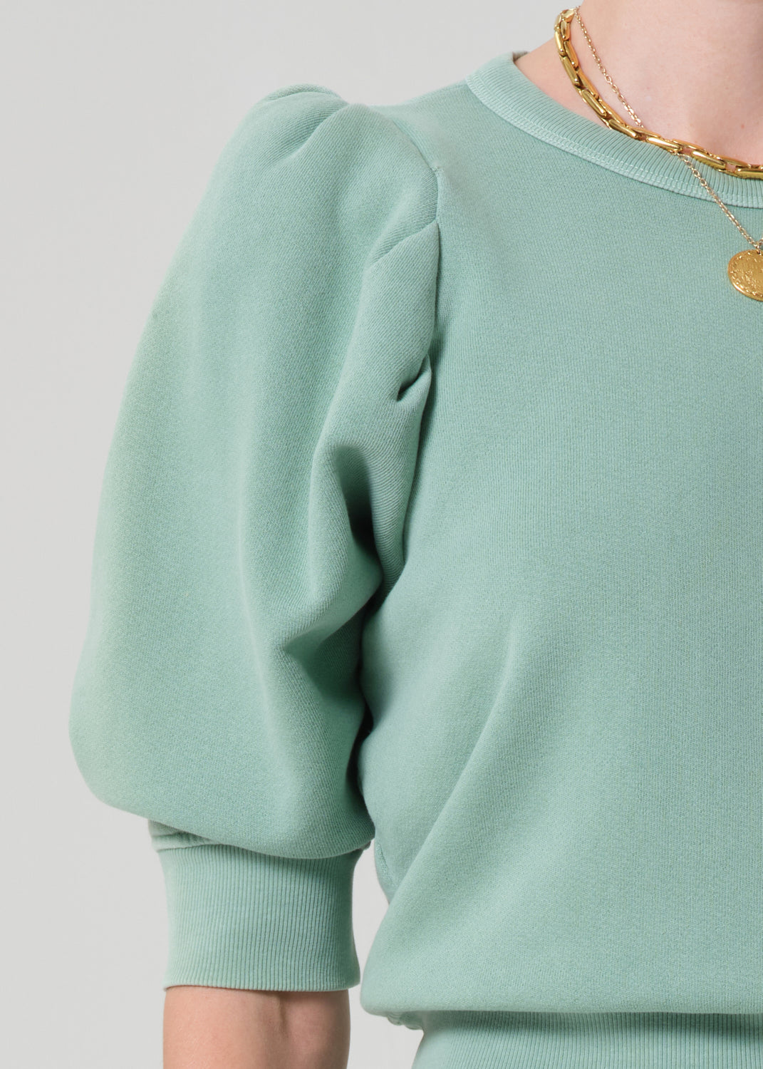 Person wearing a matching green sweater and cargo pants on a light gray background