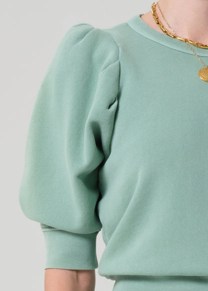 Person wearing a matching green sweater and cargo pants on a light gray background