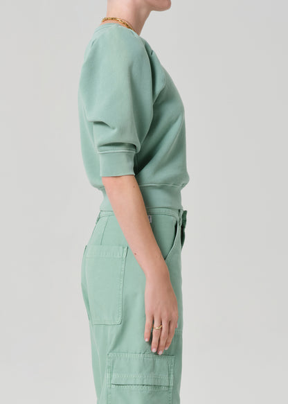 Person wearing a matching green sweater and cargo pants on a light gray background