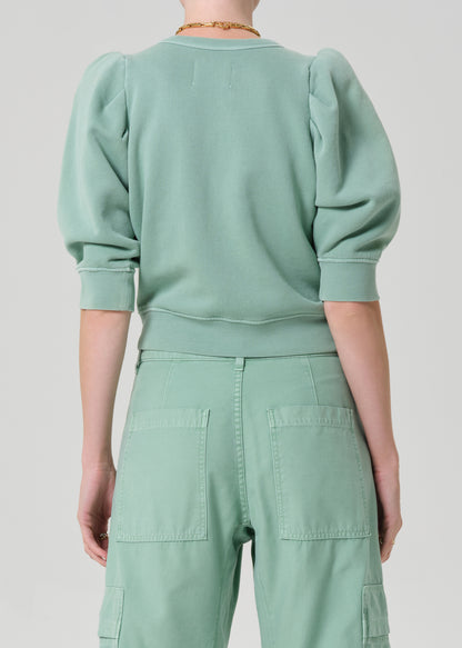 Person wearing a matching green sweater and cargo pants on a light gray background