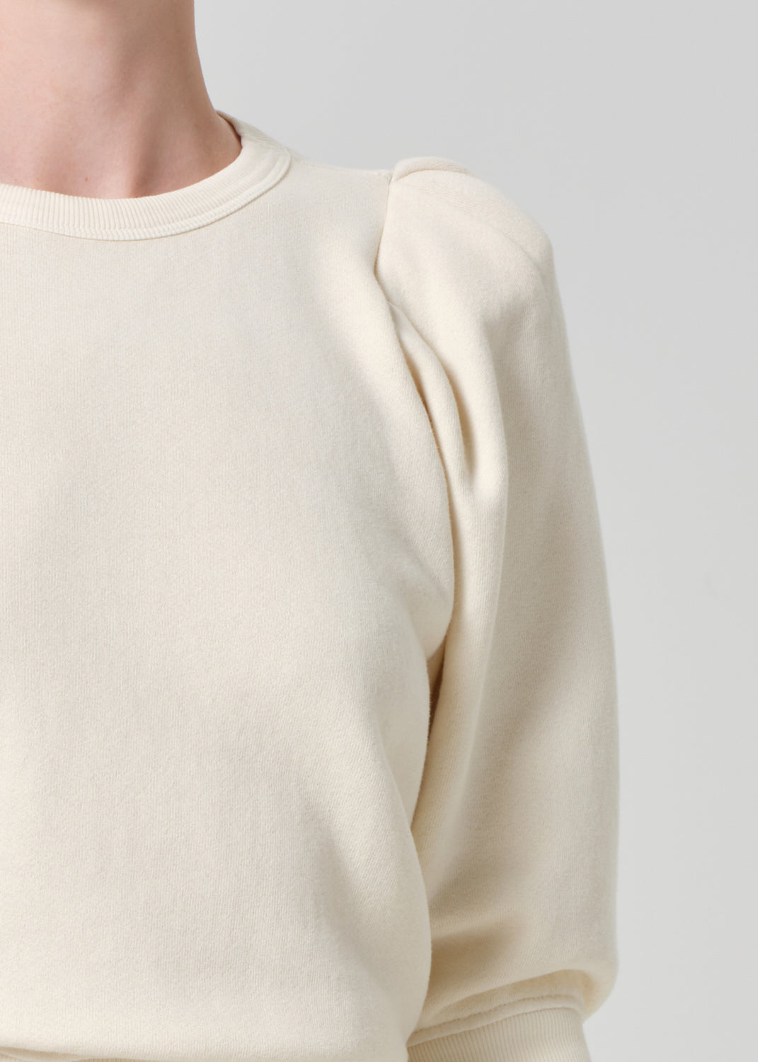 Person wearing a cream sweater on a gray background