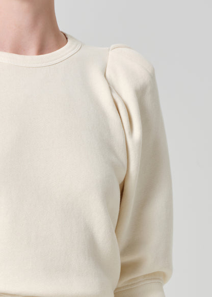 Person wearing a cream sweater on a gray background