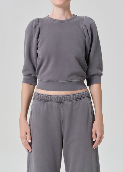 Person wearing a gray sweater and matching grey sweatpants on a light gray background