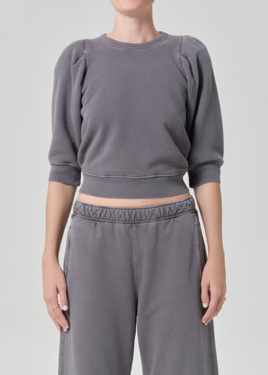 Person wearing a gray sweater and matching grey sweatpants on a light gray background