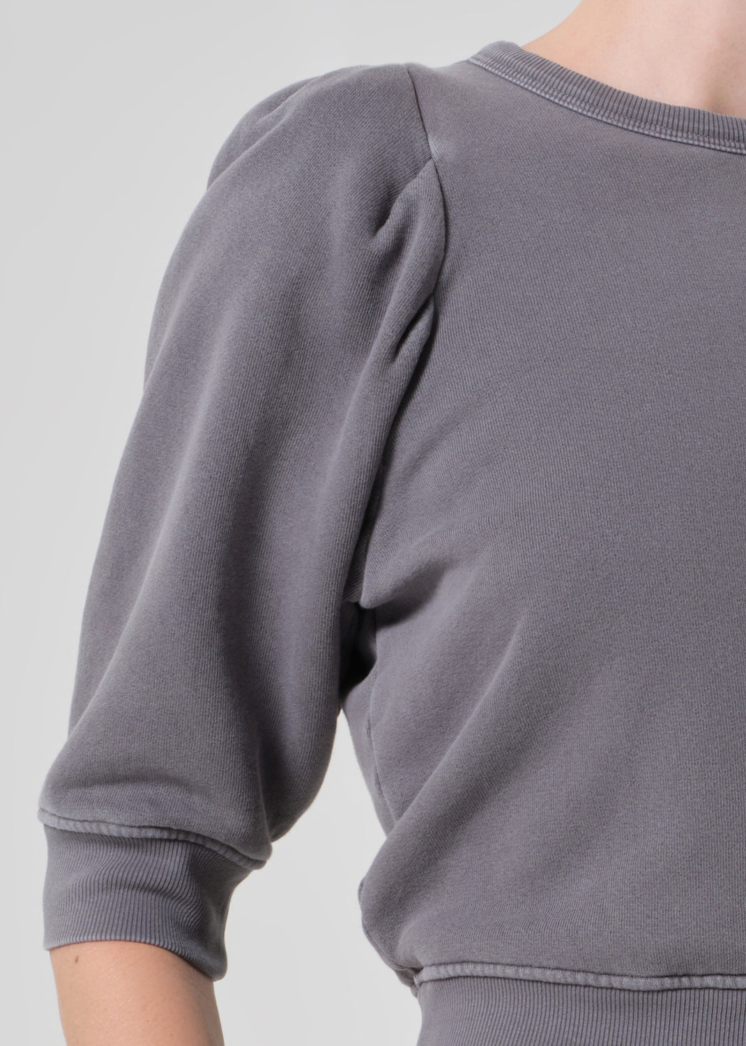 Person wearing a gray sweater and matching grey sweatpants on a light gray background