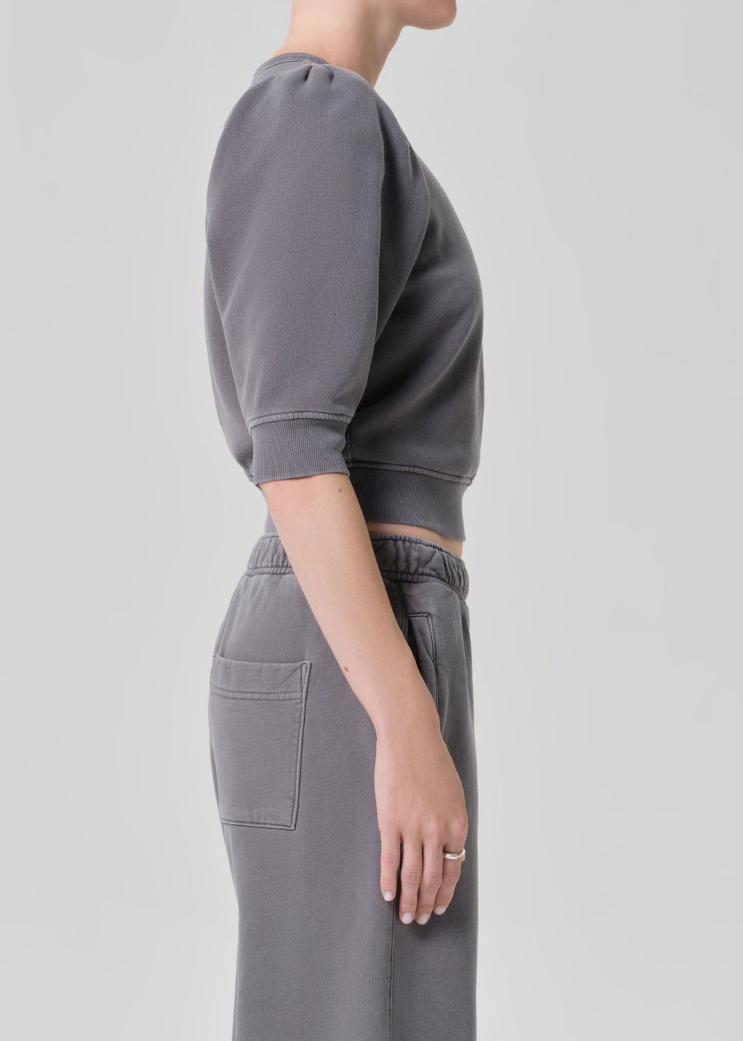 Person wearing a gray sweater and matching grey sweatpants on a light gray background