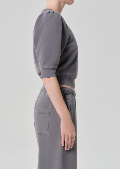 Person wearing a gray sweater and matching grey sweatpants on a light gray background