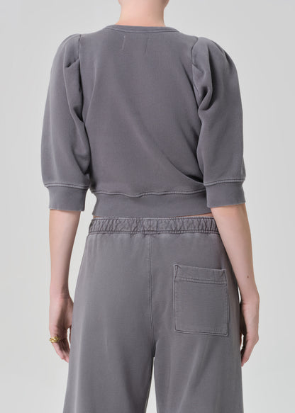 Person wearing a gray sweater and matching grey sweatpants on a light gray background