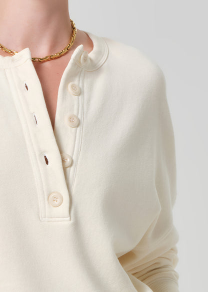 Person wearing a cream-colored sweatshirt on a gray background