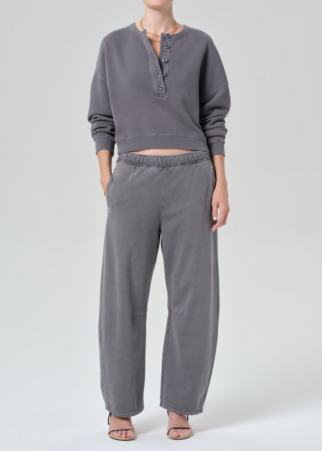 Person wearing a gray long-sleeve top and pants on a white background