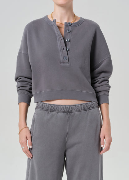 Person wearing a gray cropped sweatshirt and pants on a plain background