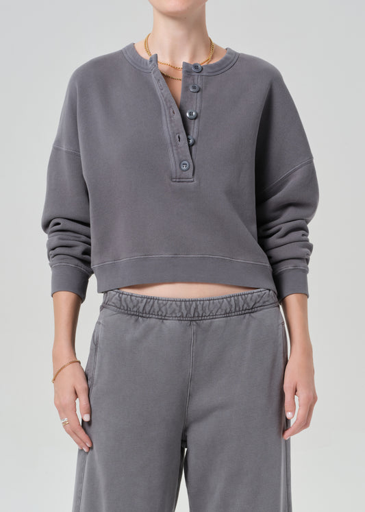 Person wearing a gray cropped sweatshirt and pants on a plain background