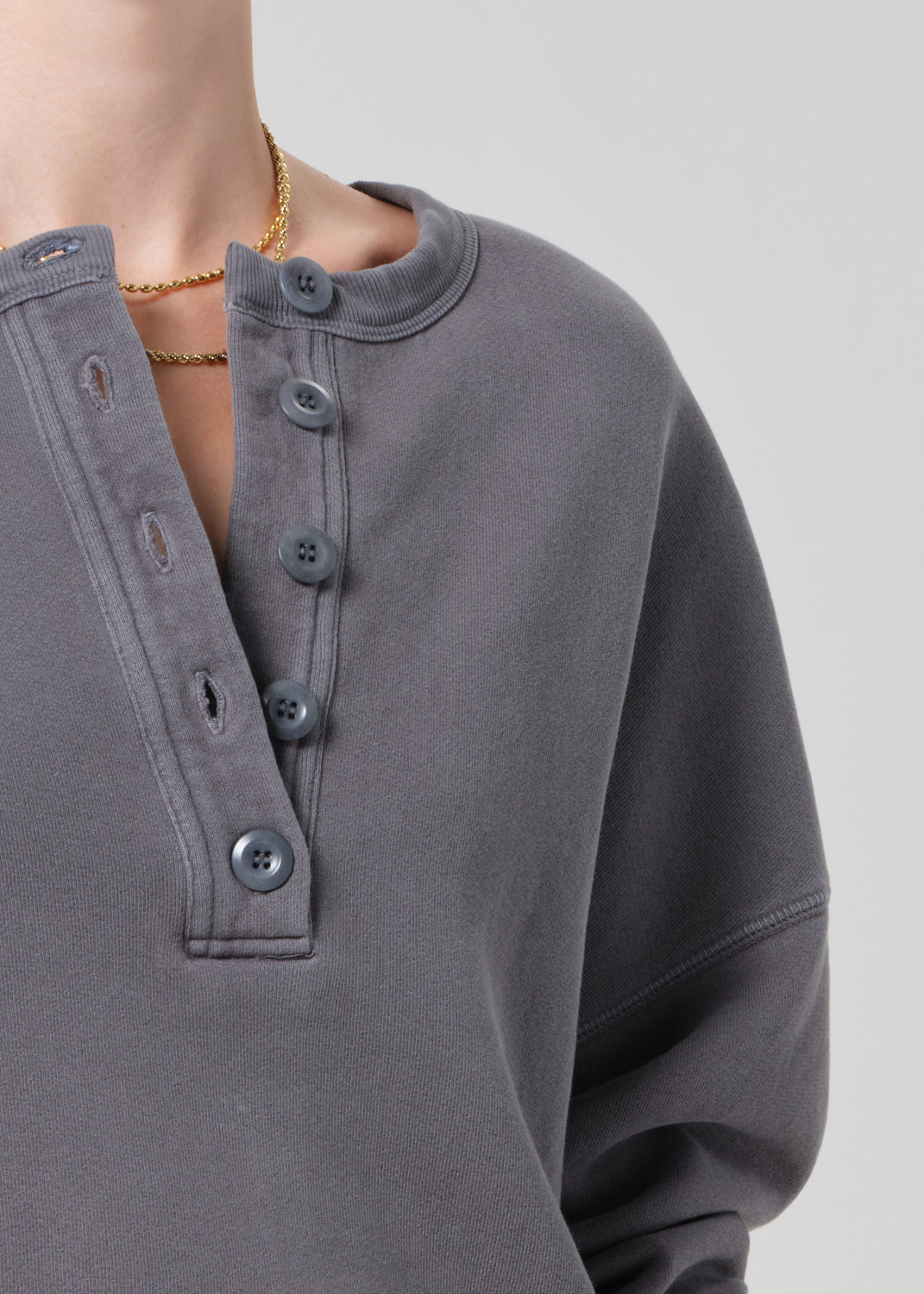 Gray button-up shirt worn by a person on a light gray background