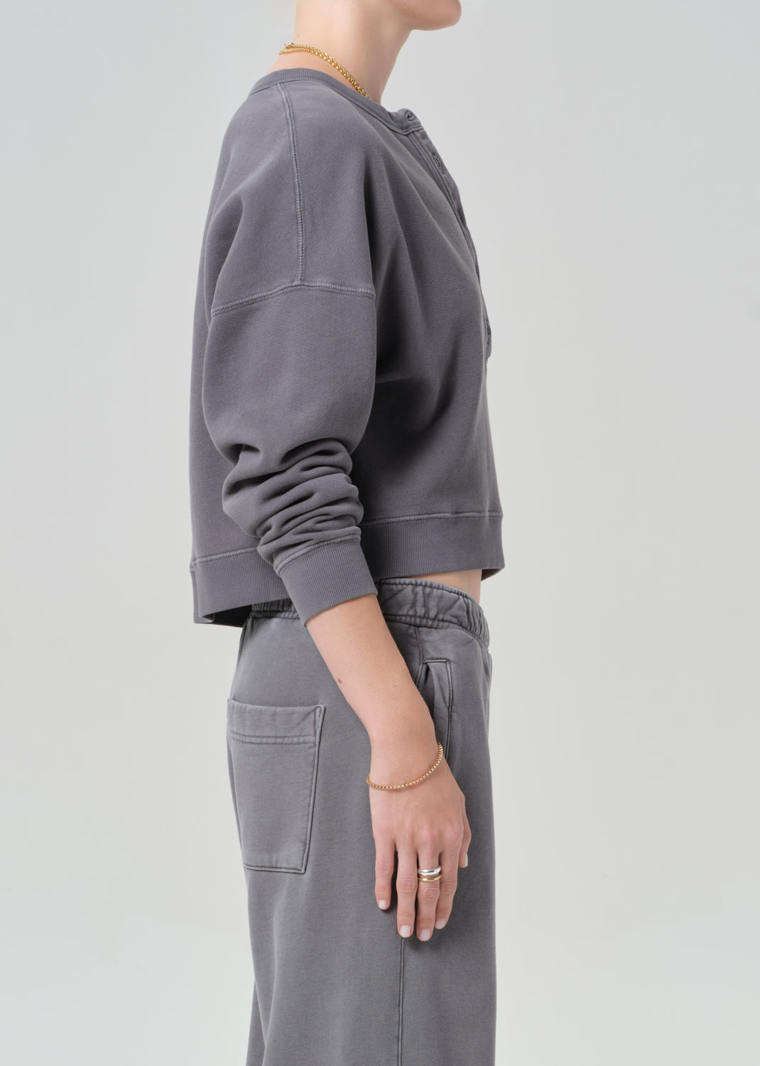 Person wearing a gray sweatshirt and pants on a light gray background