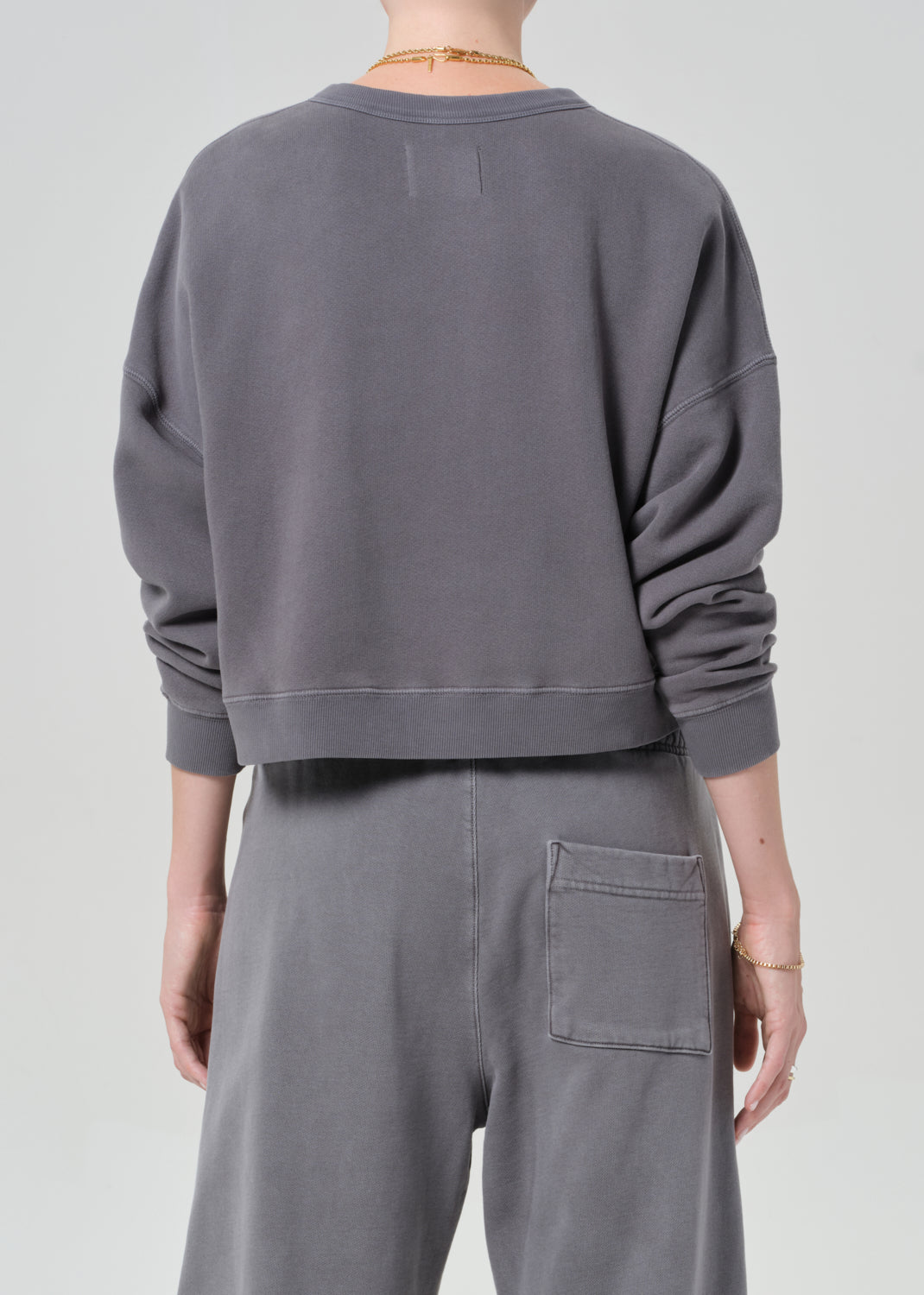 Person wearing a gray sweatshirt and pants on a plain background