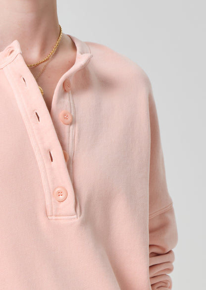 Person wearing a pink sweatshirt and beige shorts on a gray background