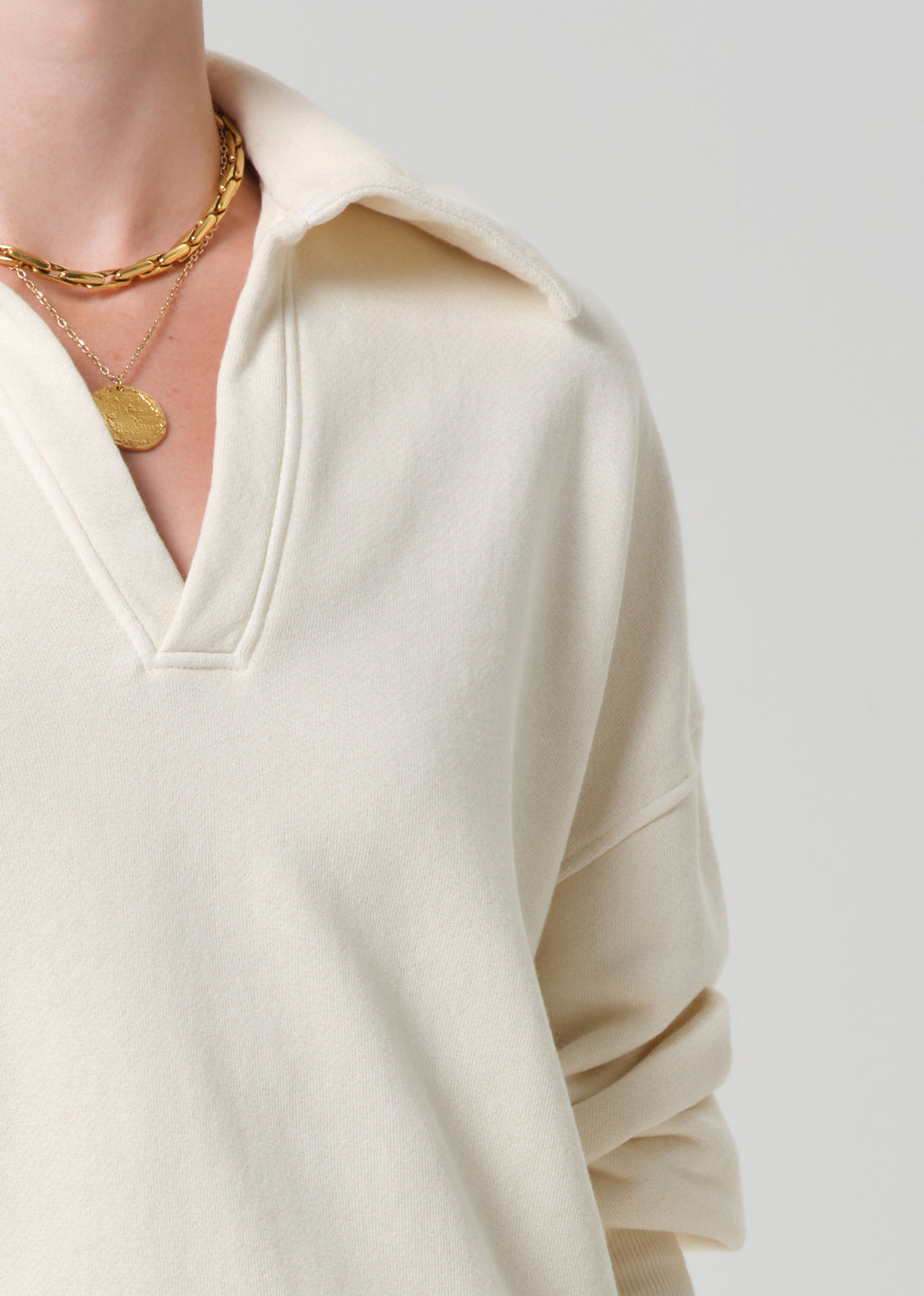 Person wearing a cream-colored sweatshirt on a plain background