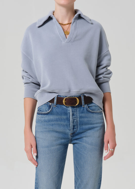 Person wearing a light blue sweater and blue jeans on a plain background