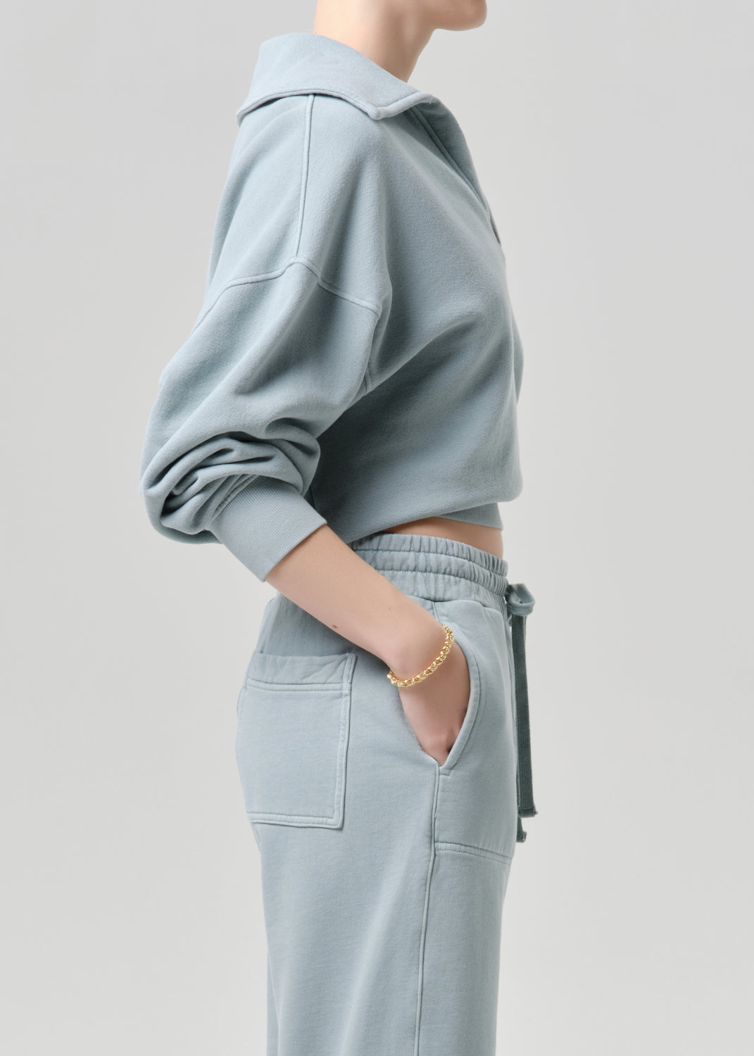 Person wearing a light blue outfit with a grey background