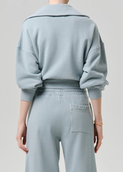 Person wearing a light blue outfit with a matching jacket and pants on a grey background