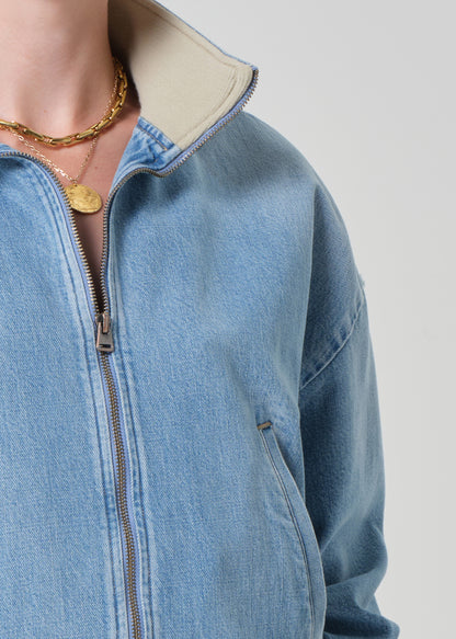 Close-up of a person wearing a blue denim jacket with a neutral background