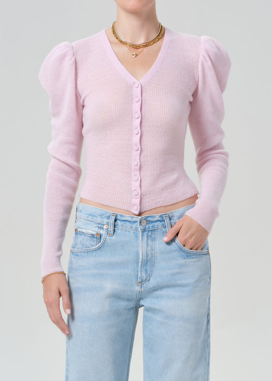 Person wearing a pink cardigan and light blue jeans on a gray background