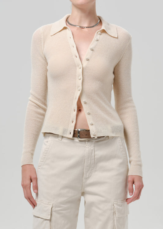 Person wearing a white cardigan on a grey background