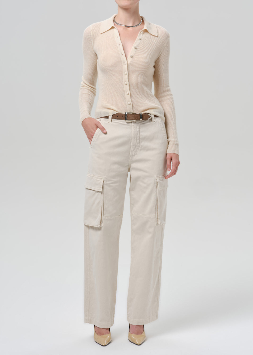 Person wearing a white cardigan on a grey background