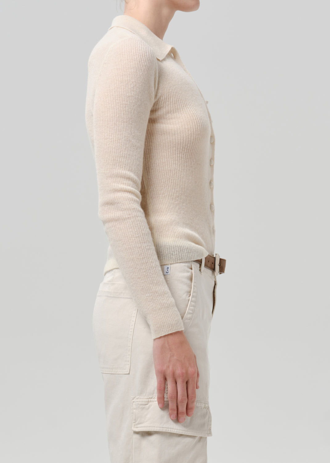 Person wearing a white cardigan on a grey background