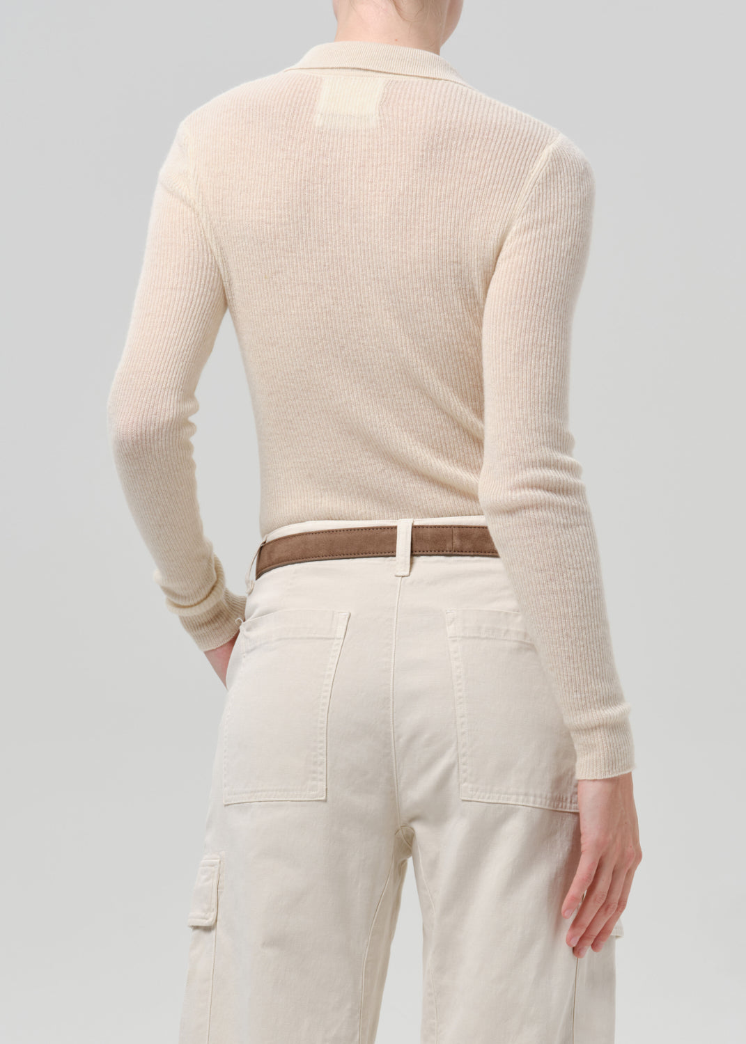 Person wearing a white cardigan on a grey background