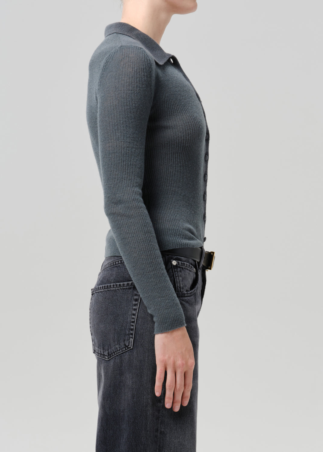 Person wearing a charcoal ribbed collared cardigan with black wide leg jeans viewed from the side on a grey background