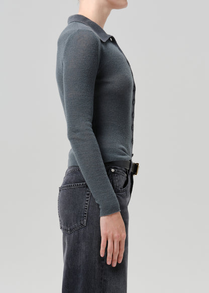 Person wearing a charcoal ribbed collared cardigan with black wide leg jeans viewed from the side on a grey background