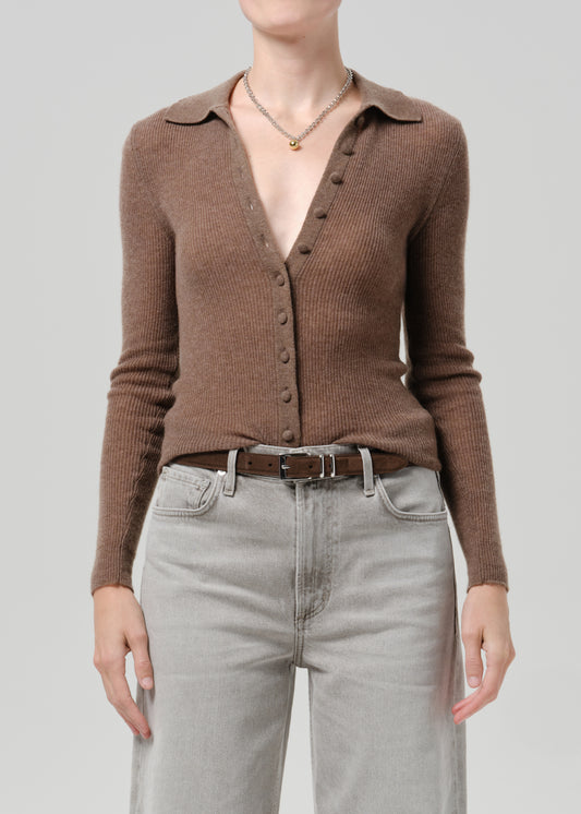 Person wearing a brown cardigan on a grey background