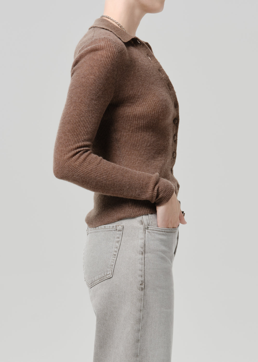 Person wearing a brown cardigan on a grey background