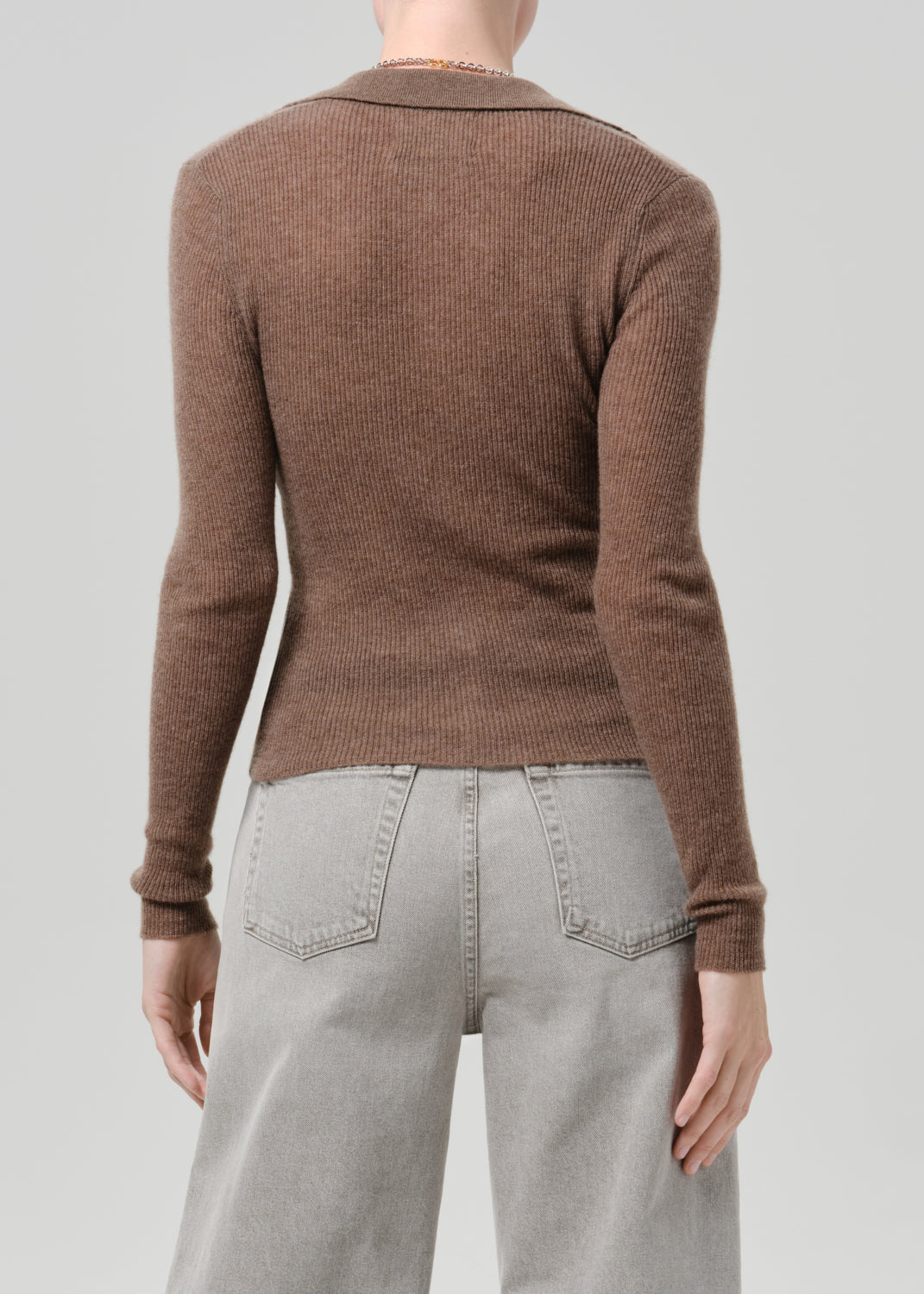 Person wearing a brown cardigan on a grey background