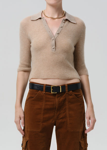 Person wearing a beige ribbed sweater and brown cargo pants on a grey background